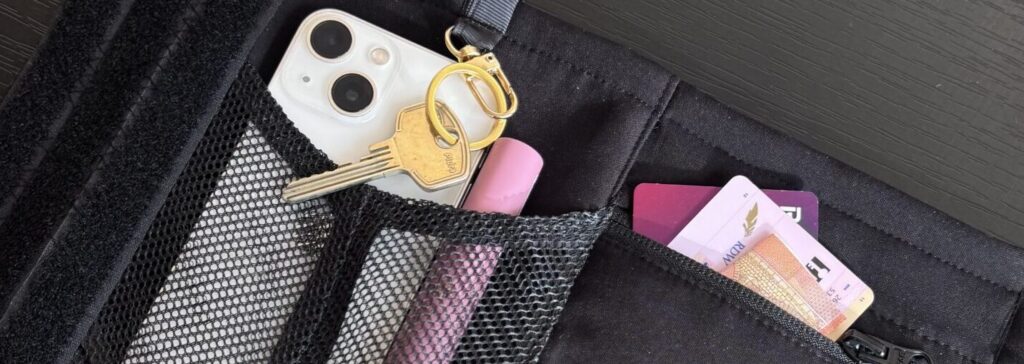 ALERA bottle pouch with multiple storage pockets holding keys, lip balm, cards and small personal items.