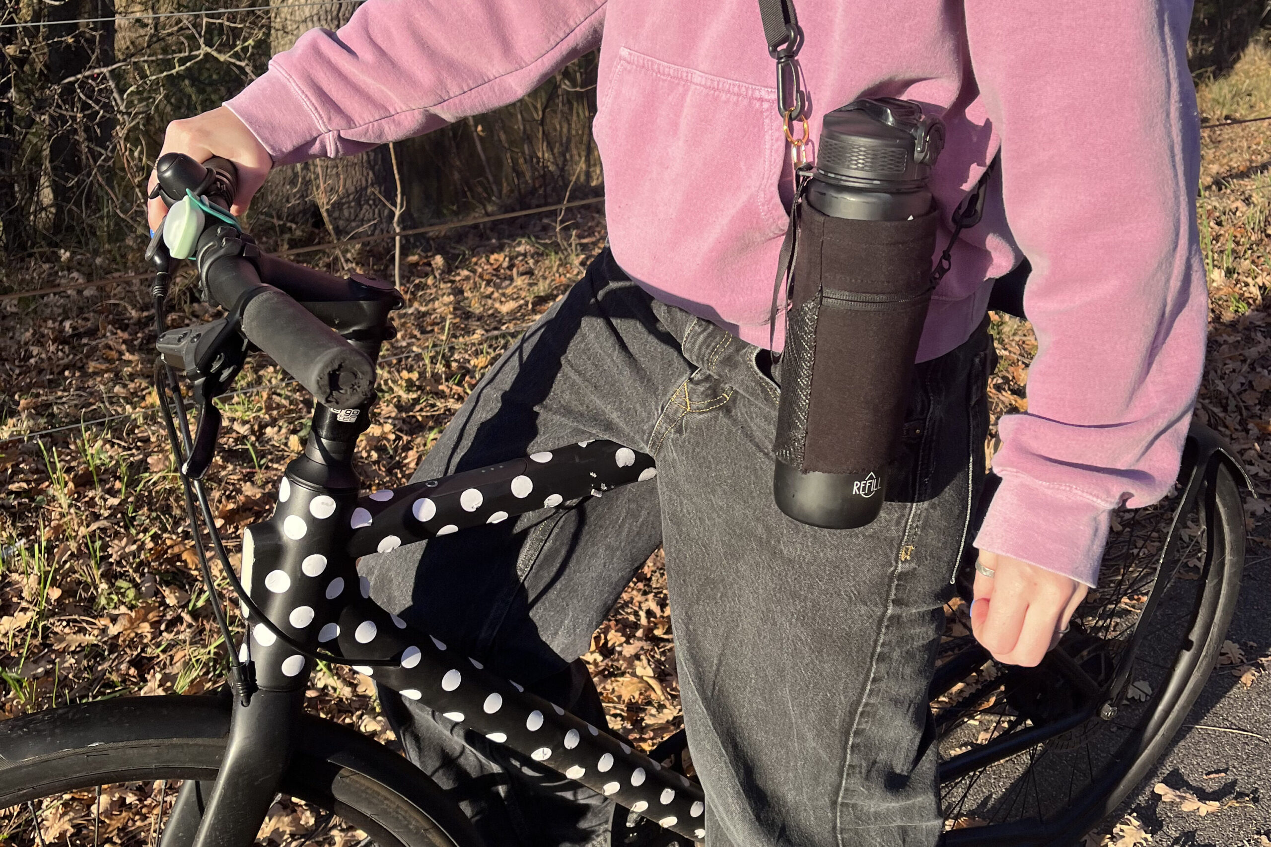 Person cycling with a water bottle fitted with the Alera storage sleeve, showing how the accessory keeps essentials secure and accessible during active use.