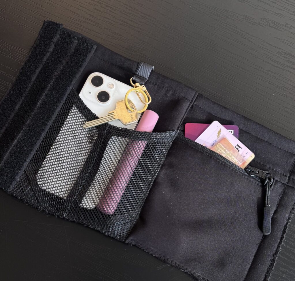 ALERA bottle pouch with multiple storage pockets holding keys, lip balm, cards and small personal items.